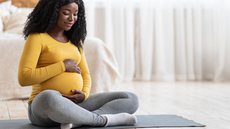 smiling pregnant woman holding belly