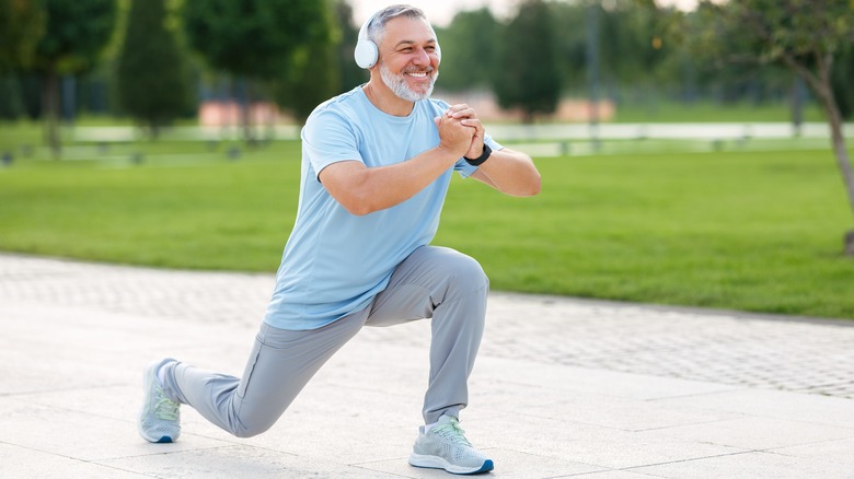 man with headphones stretching outdoors