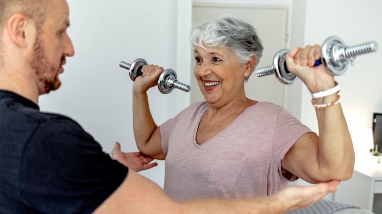 woman lifting weights with trainer