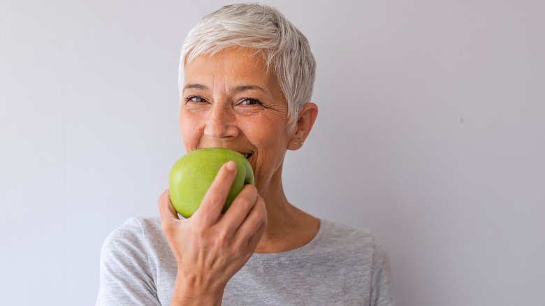 older woman eating green apple