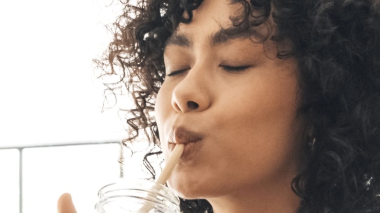 woman sips water through straw