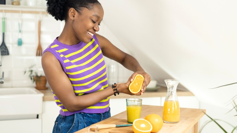 african american woman makes fresh-squeezed orange juice