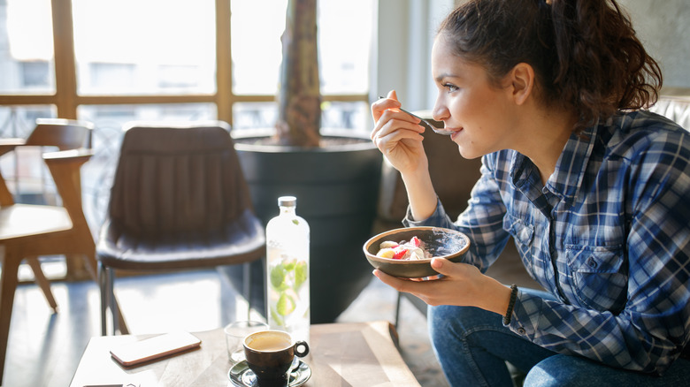 woman eating whole grain cereal and drinking tea and infused water