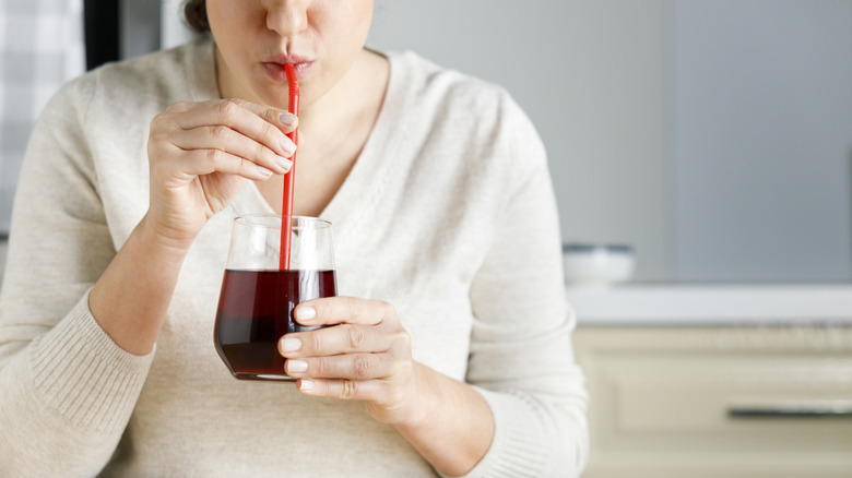 A woman drinking pomegranate juice with a straw