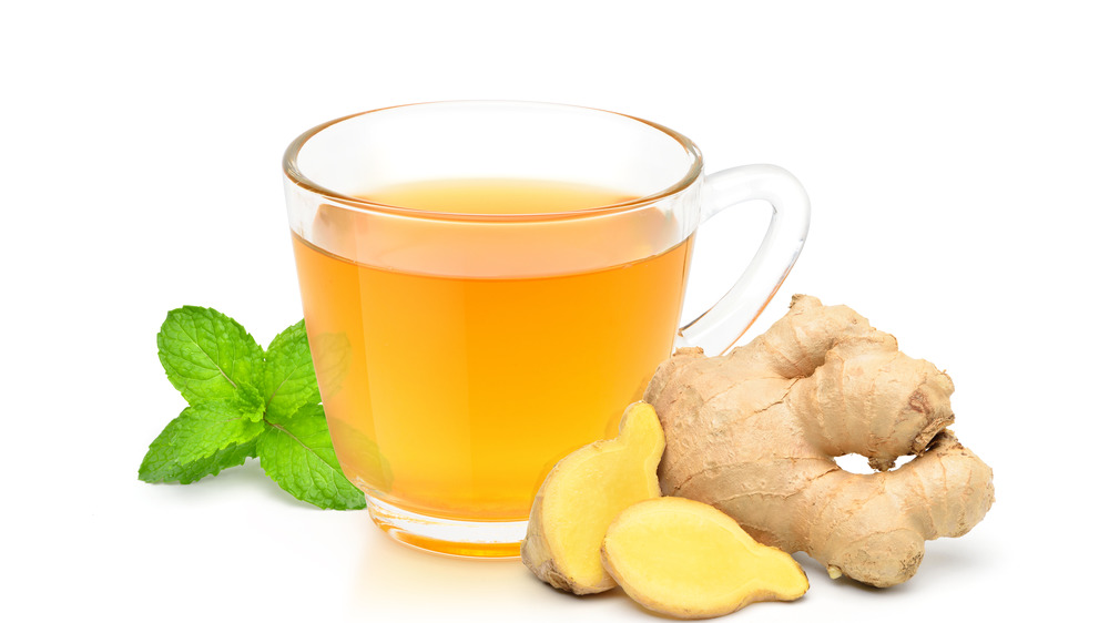 Glass of ginger tea with fresh sliced ginger and mint