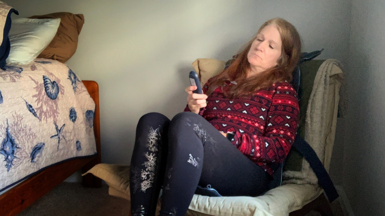 A woman using a remote while sitting on a back massage cushion