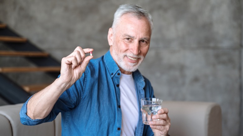 older man holding a multivitamin