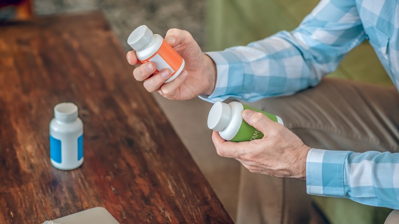 man's hands holding supplement bottles