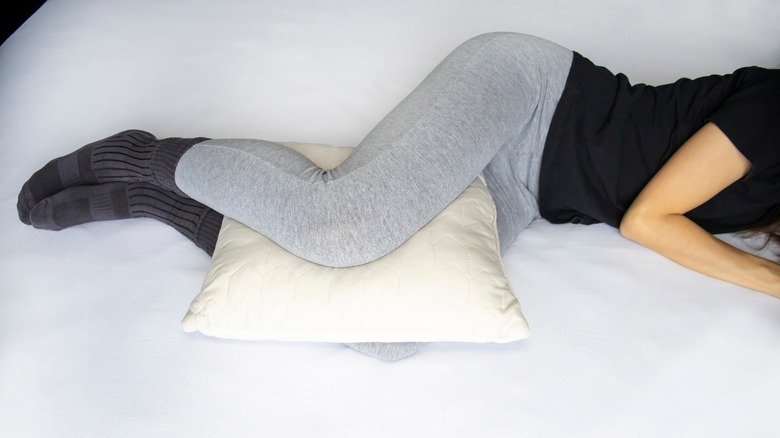 Pillow between legs of woman