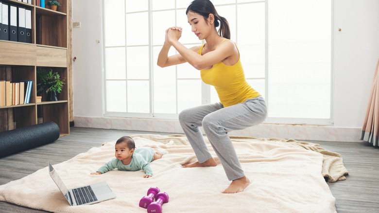 woman exercising next to baby