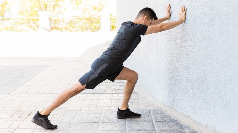 man stretches calves using wall