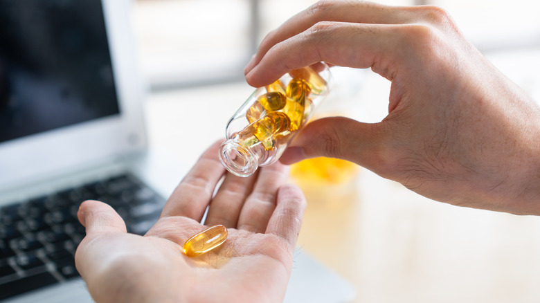 Pouring gel capsule supplements into palm of hand