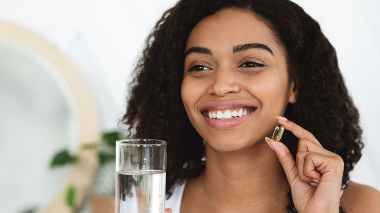 woman holding vitamin and water smiling