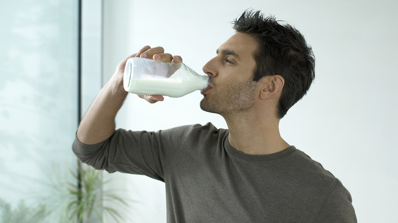 man drinking a small bottle of milk