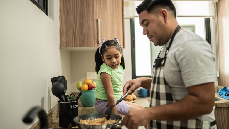 Father and daughter cooking eggs breakfast