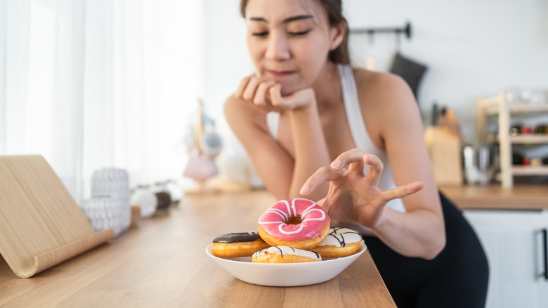 woman taking donut off plate