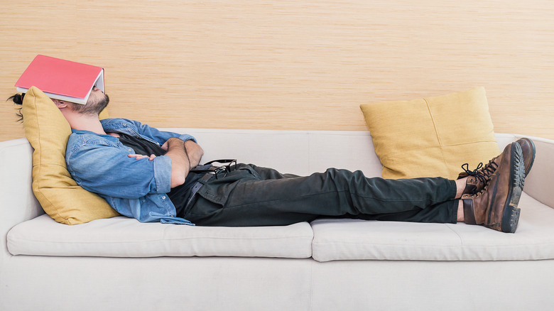 Man napping on couch with book over his face