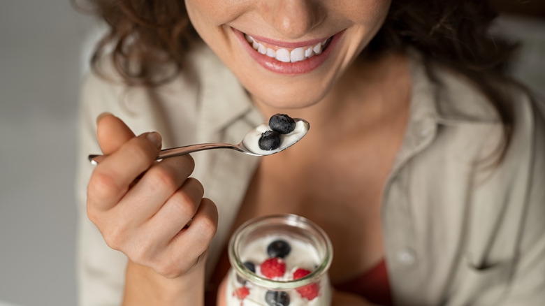 Woman smiling while eating yogurt with berries