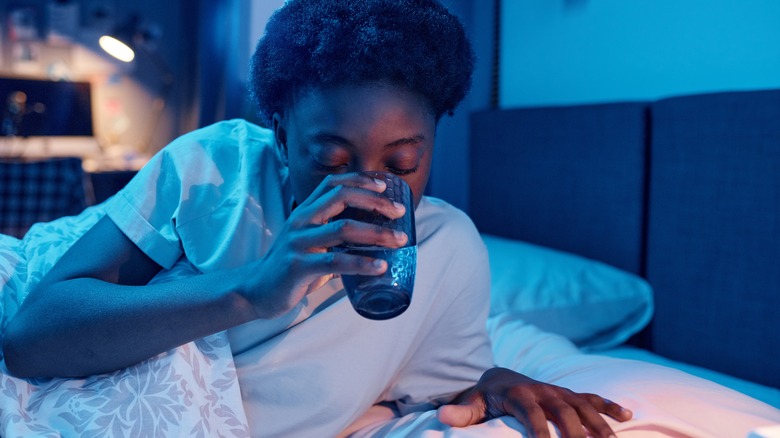 woman drinking water in bed