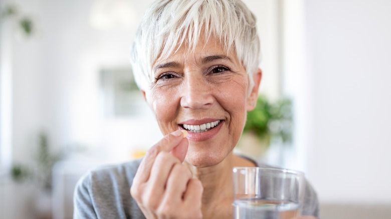 woman taking supplement and smiling