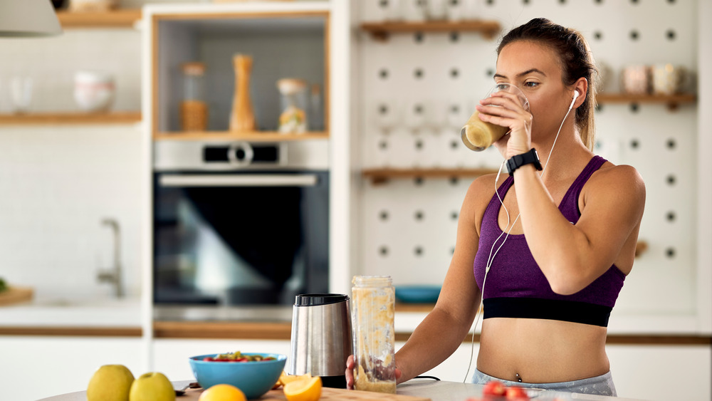 Sporty young woman drinking  a smoothie pre workout 