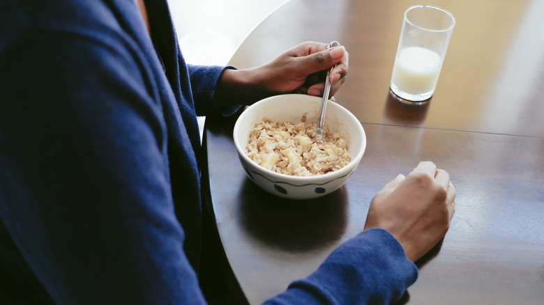 woman holding spoon ready to eat oatmeal at table