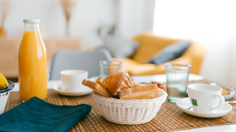 orange juice next to a basket of bread