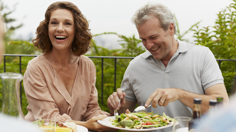 Two older adults eating a salad