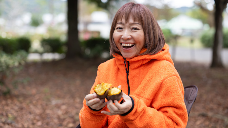 woman holding a baked sweet potato