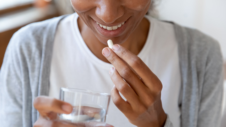 Smiling woman takes a supplement for healthy nails