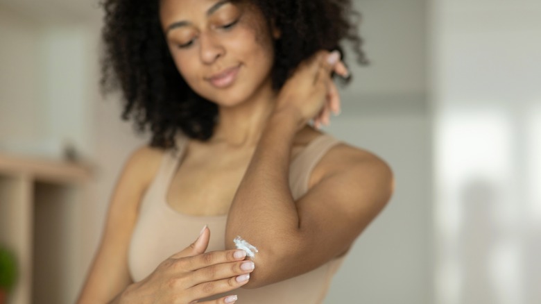 Smiling woman applying elbow cream