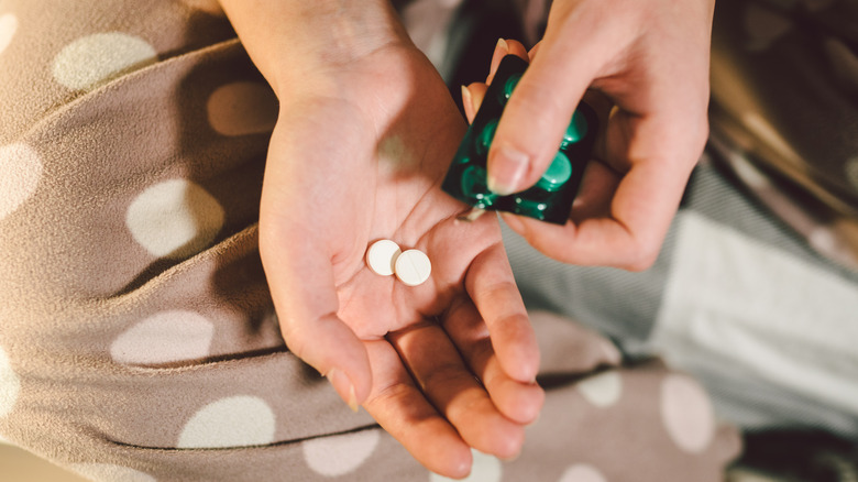 Hand holding two white pills