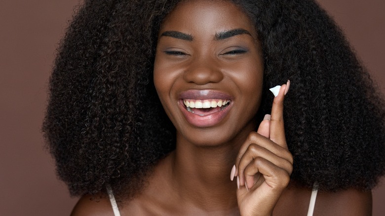 Woman smiling with a dollop of sunscreen