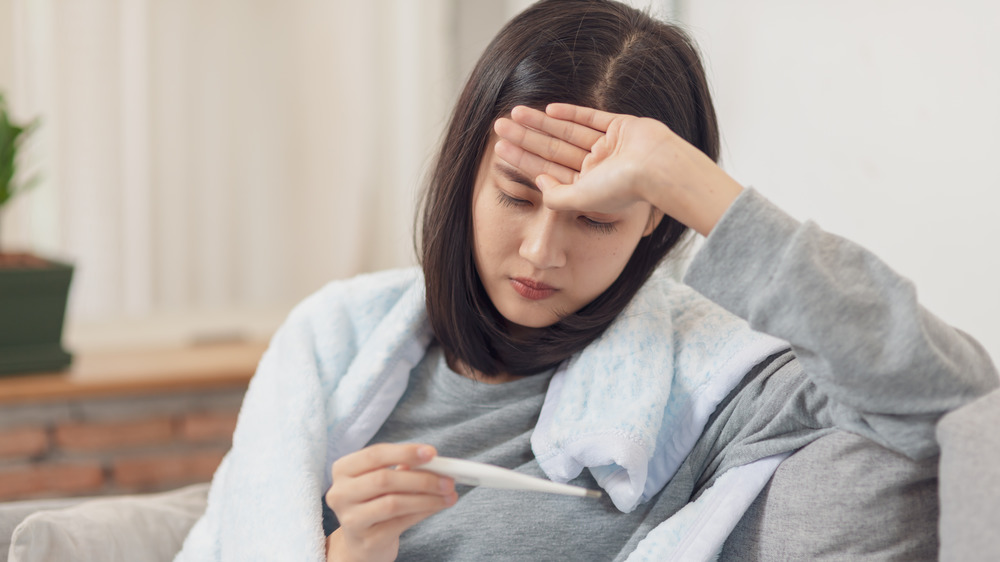 Woman taking temperature with thermometer