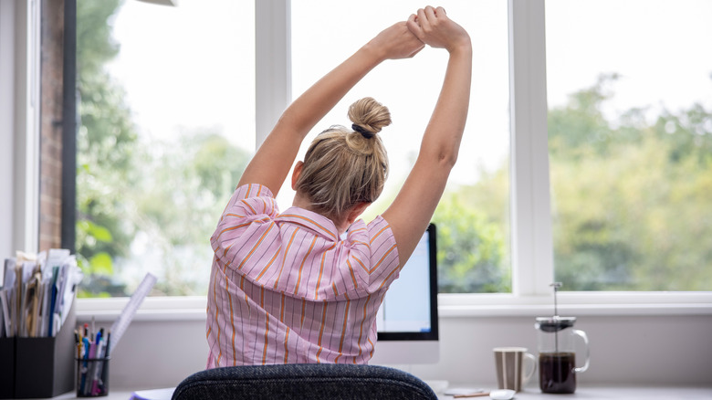 a woman stretching at her desk