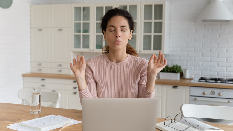 Woman meditating while working from home