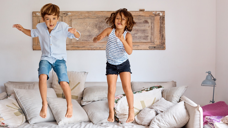 Energetic boy and girl jumping on the couch