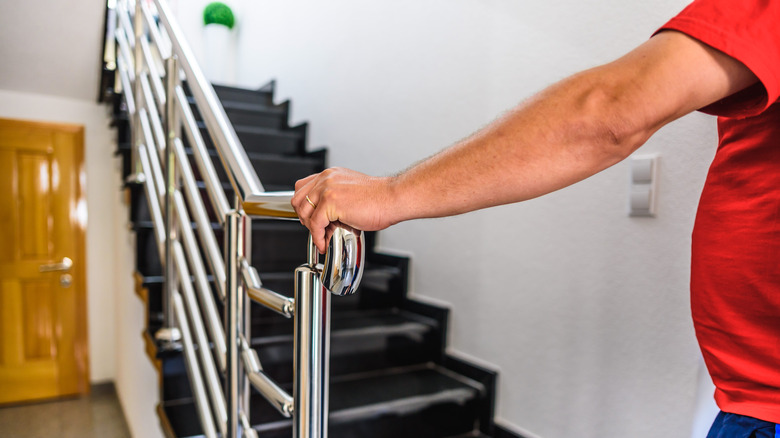 someone uses the railing on a staircase