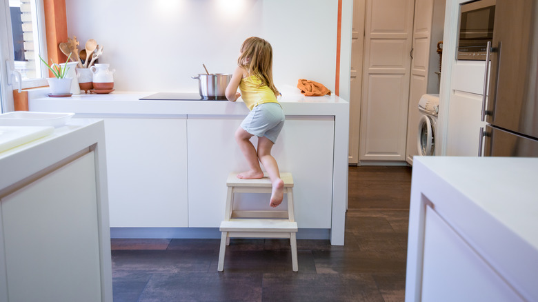 a child climbs a stool for something