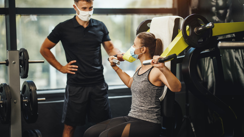 Woman performing exercise with trainer