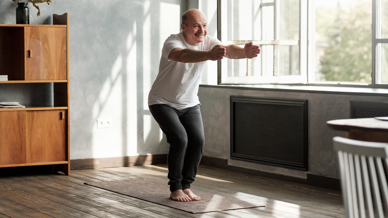 Older man doing chair yoga pose indoors