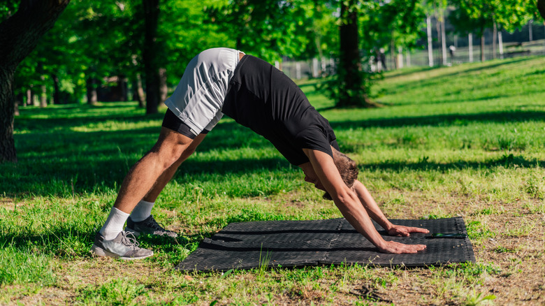 A man performs a Downward Facing Dog yoga position