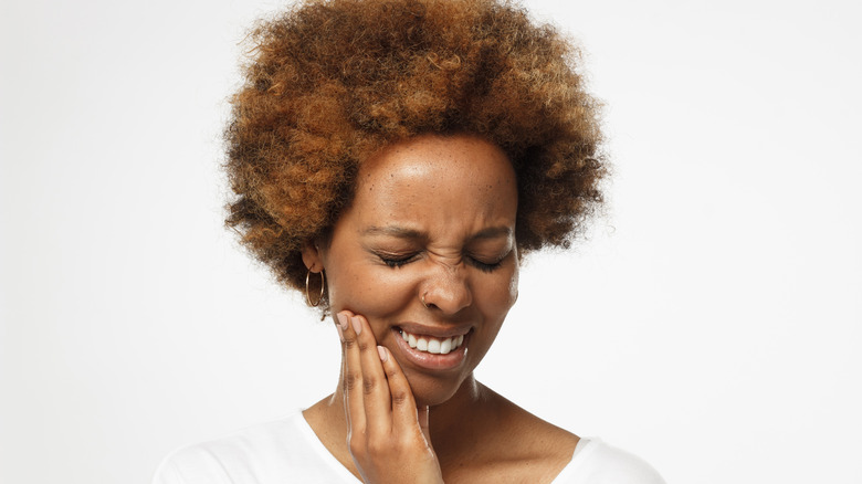 woman massaging her jaw in pain