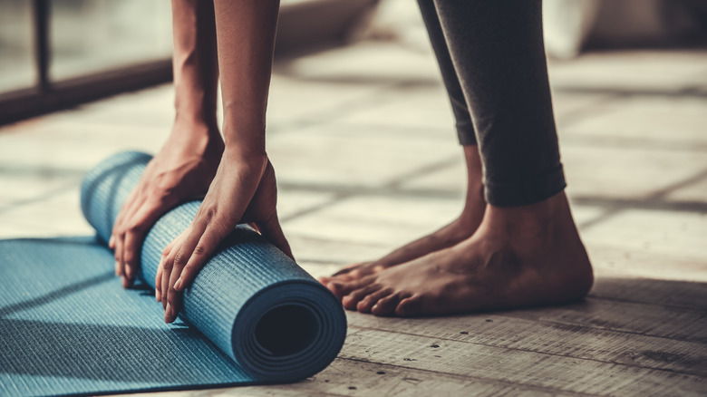 a woman rolling out a yoga mat