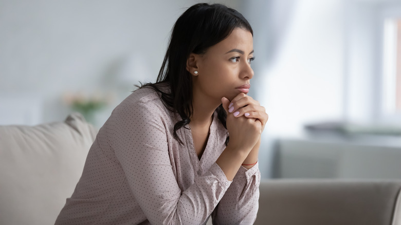 woman sitting on couch looking pensive and lost in thought