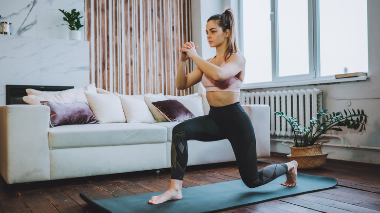 A woman performs a lunge at home