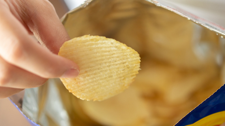 Hand reaching into bag of chips