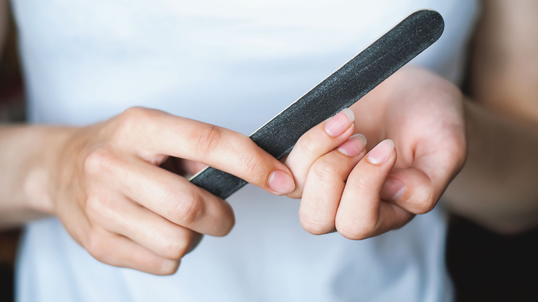 Close up of hand holding a nail file and filing their nail