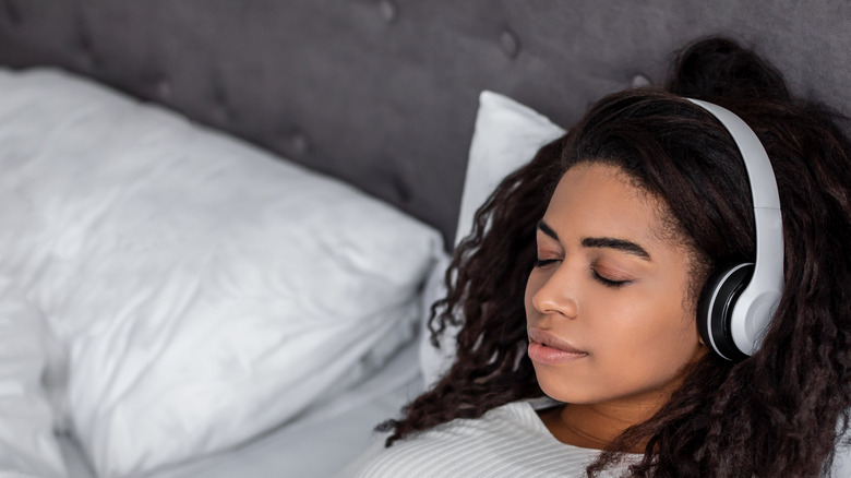 young woman relaxing in bed with headphones