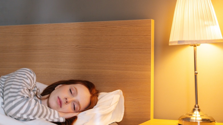 A woman laying in bed with the lights on